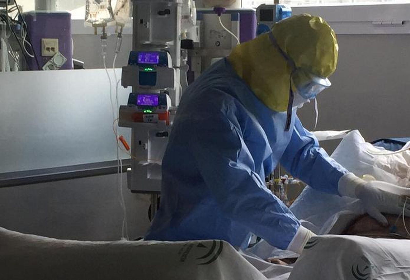 Una fisio protegida con un EPI trata a un paciente ingresado en un centro hospitalario.