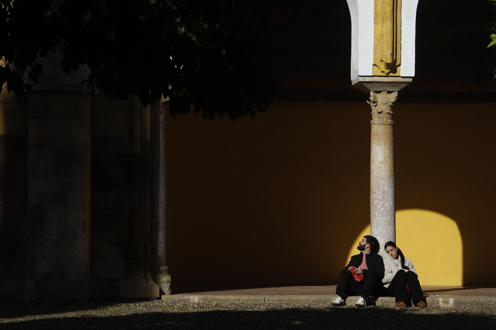 Unos jóvenes toman el sol en el Patio de los Naranjos.