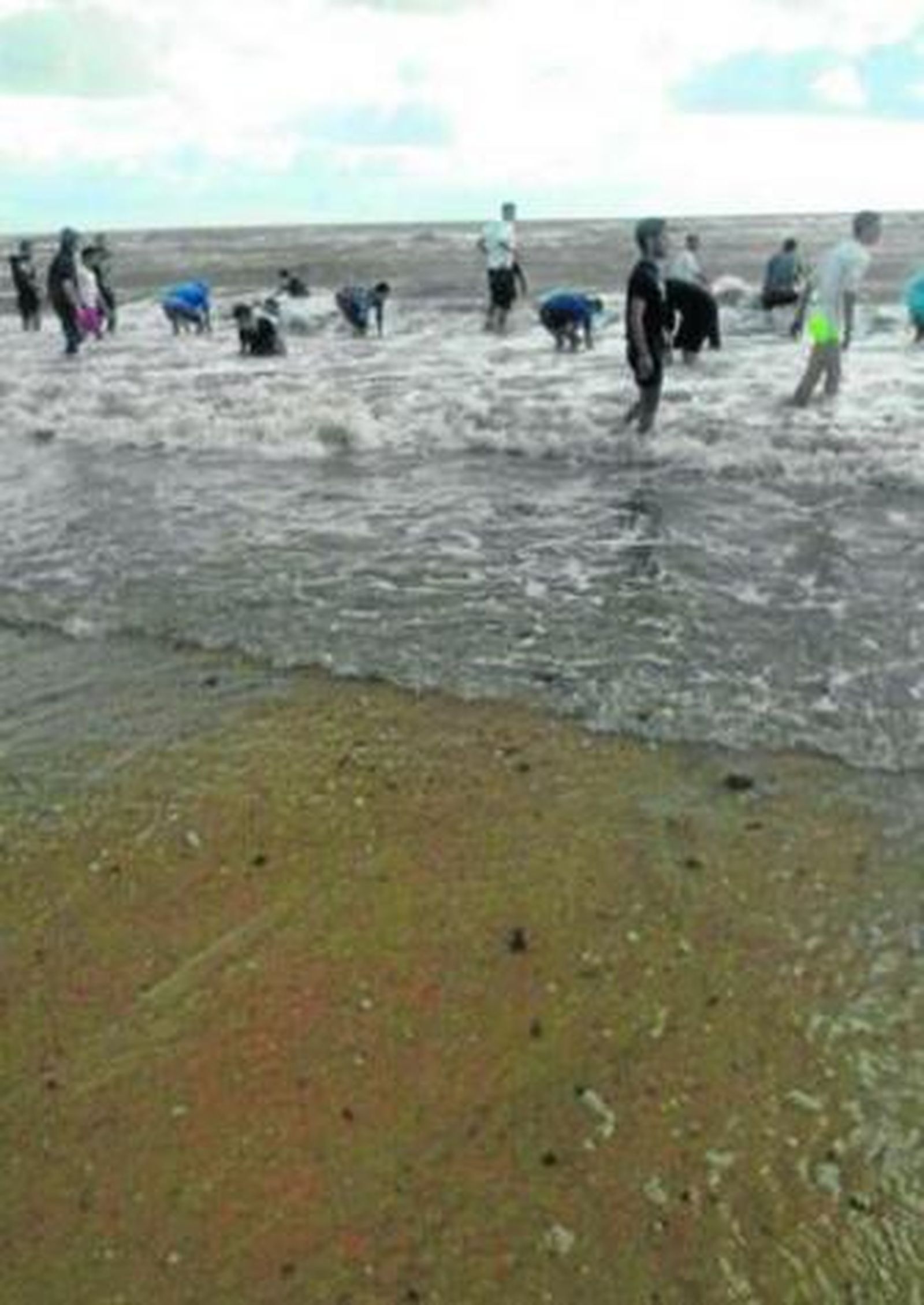 Jóvenes se adentran en la orilla de la playa de La Barrosa a la busca de hachís, el pasado miércoles.