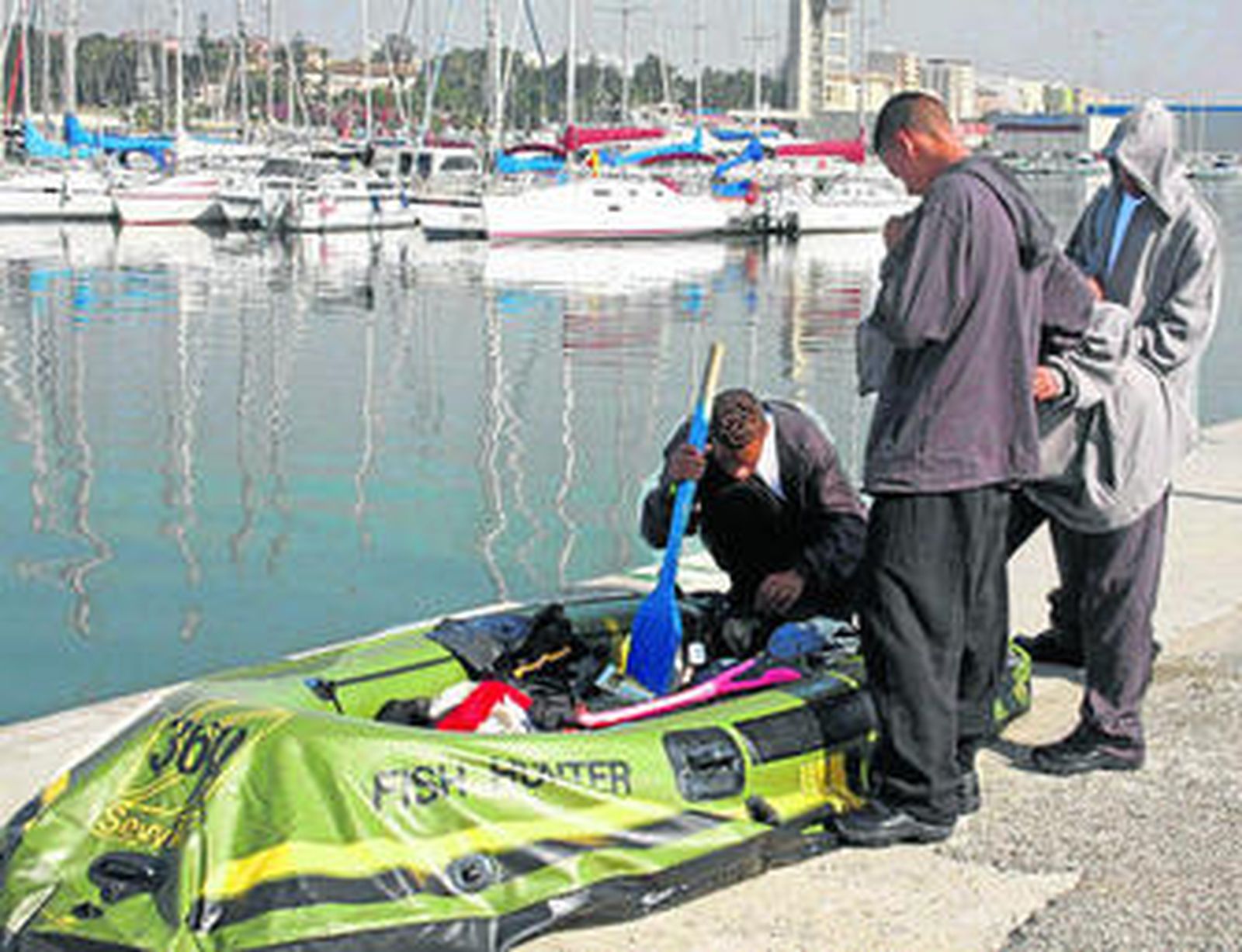Cuatro de los inmigrantes interceptados ayer en el Estrecho, junto a la balsa de juguete en la que viajaban.