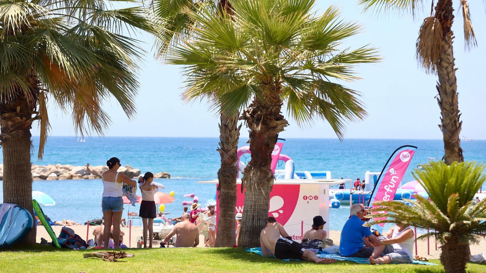 Personas a la sombra de las palmeras para evitar el calor.