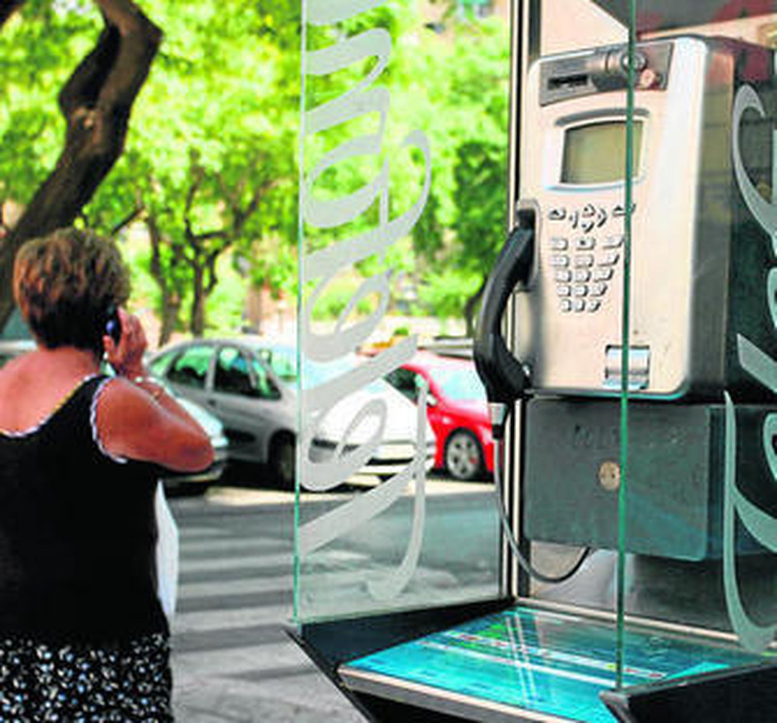 Una señora pasa junto a una cabida de Telefónica.