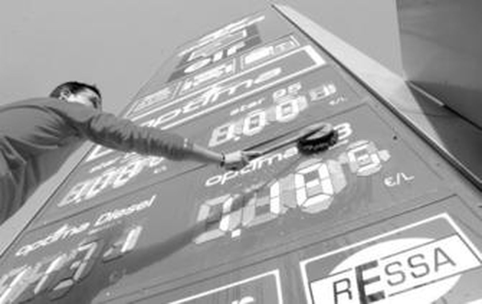 Un trabajador de una gasolinera de la zona norte limpia el poste con los nuevos precios del combustible tras la última bajada.