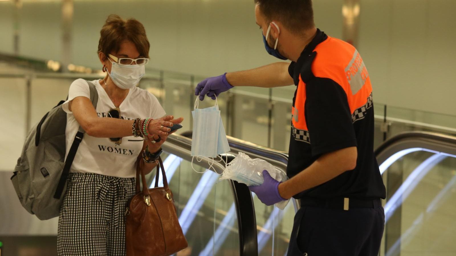 Un voluntario de Protección Civil entrega una mascarilla este lunes
