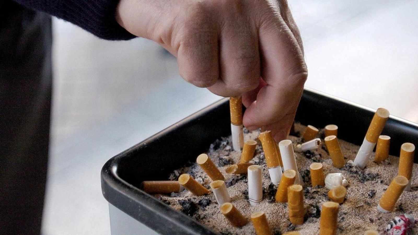 Un fumador apaga un cigarrillo.