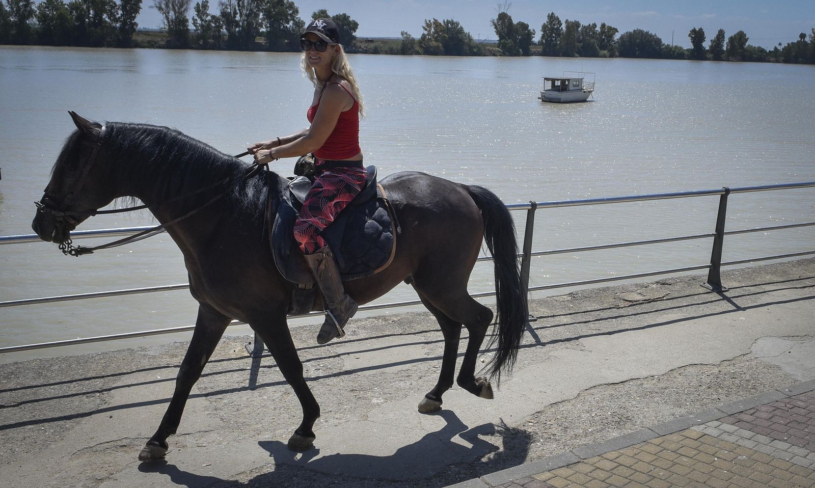 Una mujer cabalga en un caballo en la ribera del Guadalquivir a su paso por La Puebla del Río (Sevilla).