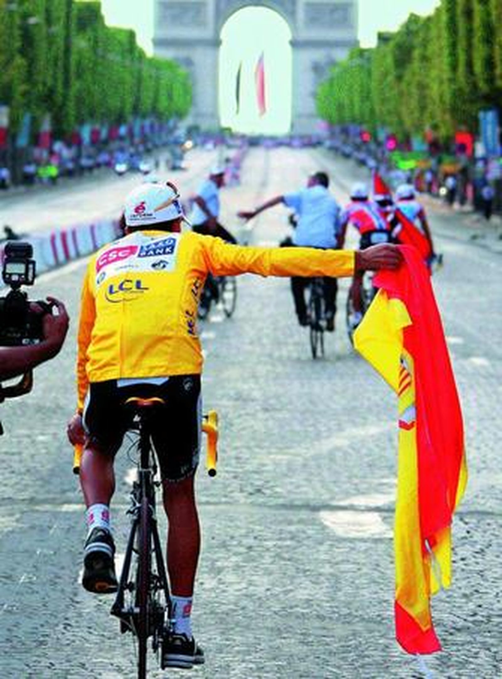 Carlos Sastre pasea la bandera de España por los Campos Elíseos de París.