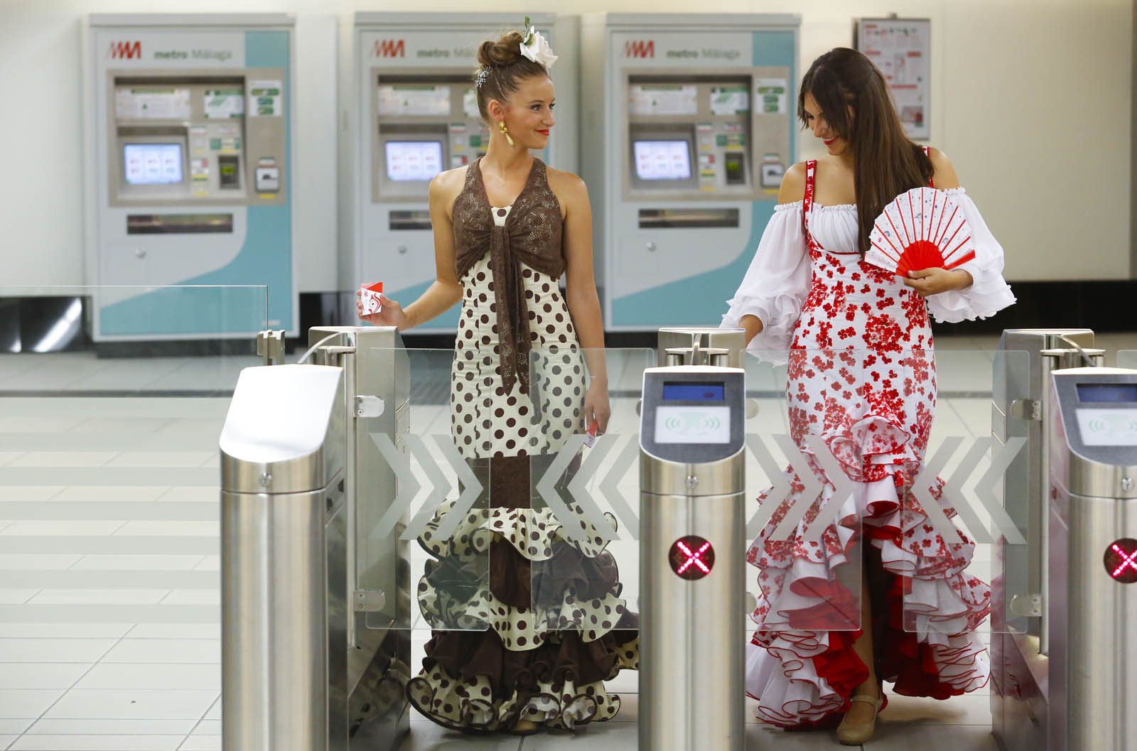 Dos mujeres vestigadas de flamenco usan el Metro.