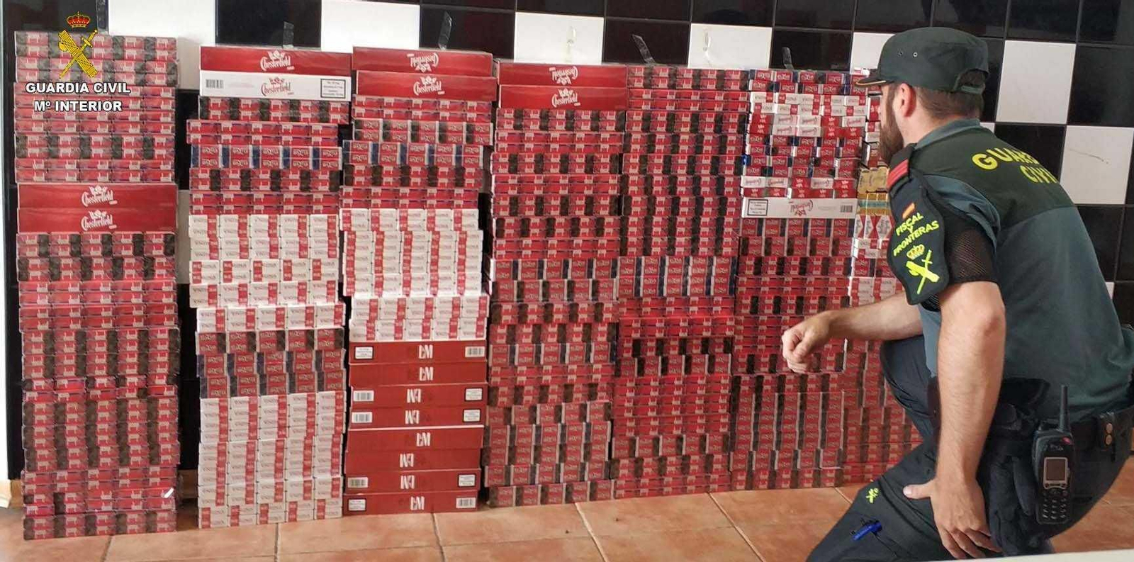 Uno de los agentes inspecciona las cajetillas de tabaco de contrabando aprehendidas en Isla Cristina.