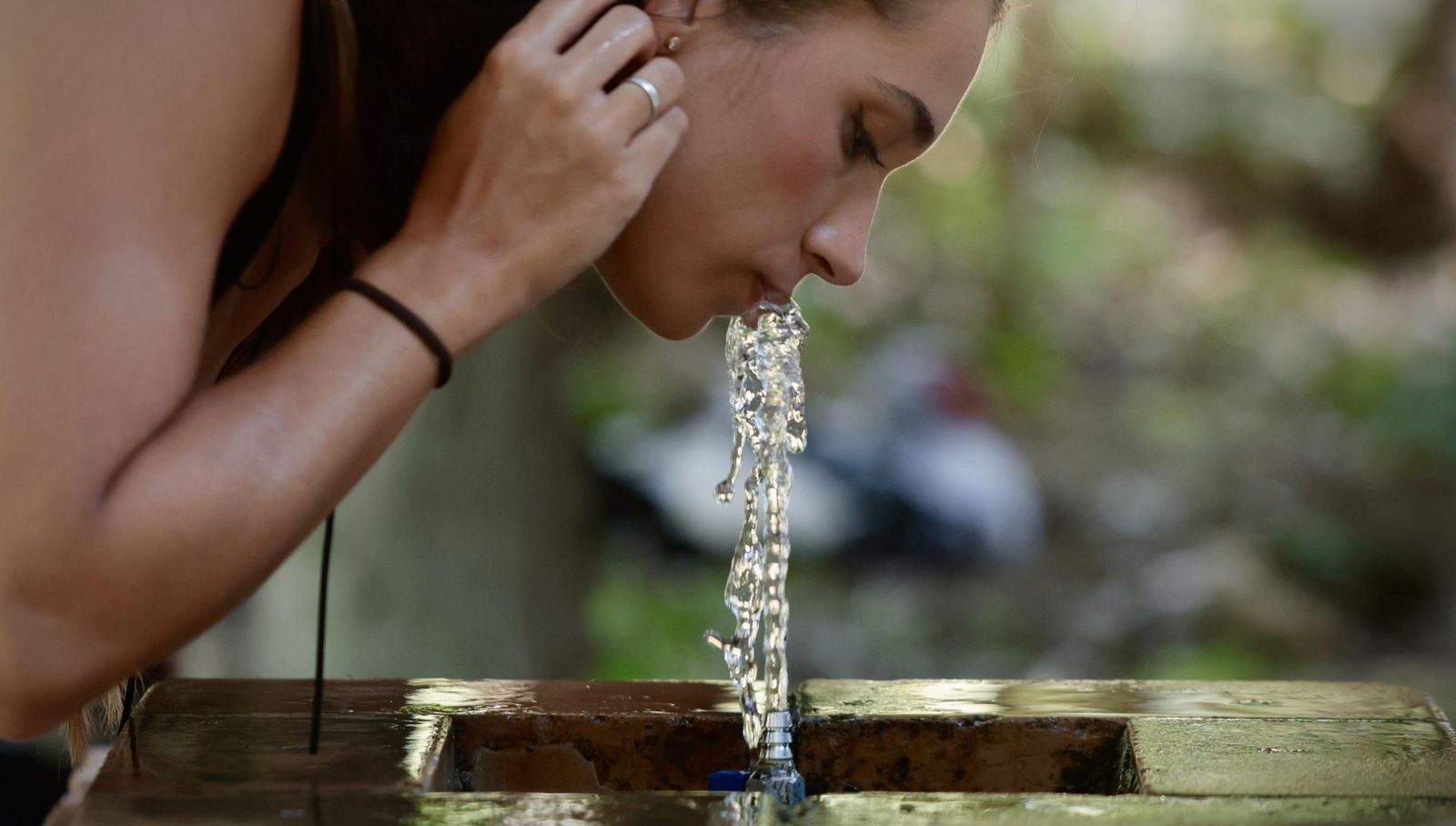 Una turista se refresca en la fuente del Parque de María Luisa.