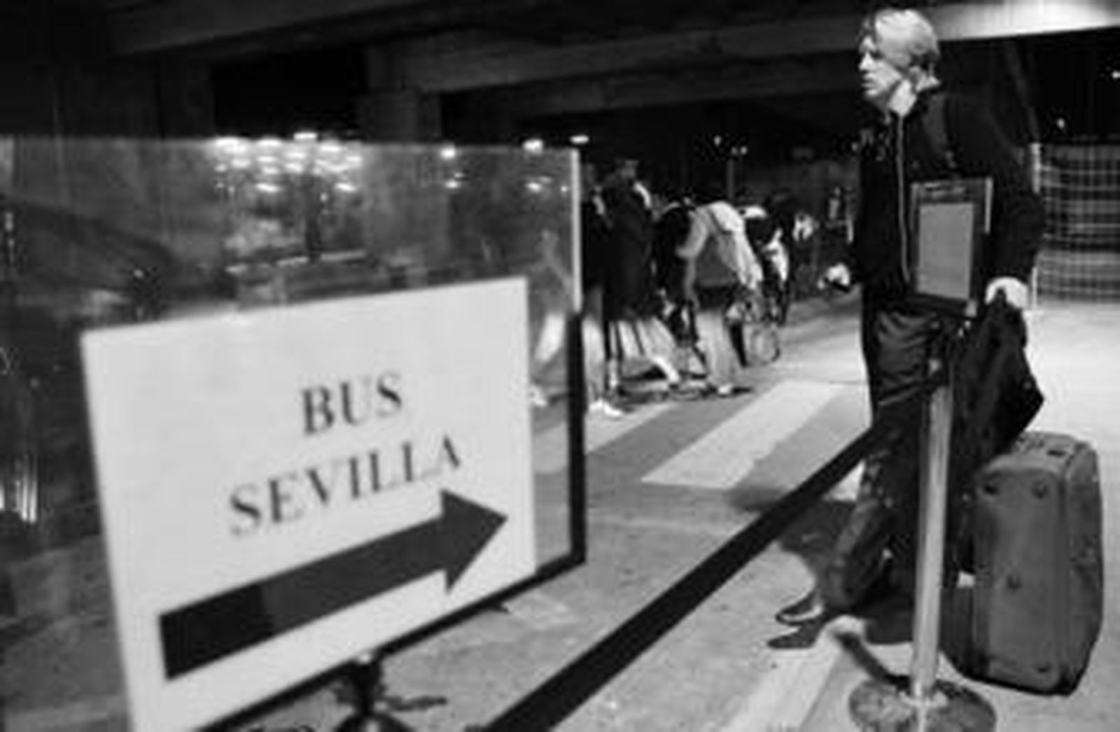 Un turista se dispone a cruzar la calle para dirigirse a tomar el autobús que le lleve a la ciudad, anoche en el aeropuerto.