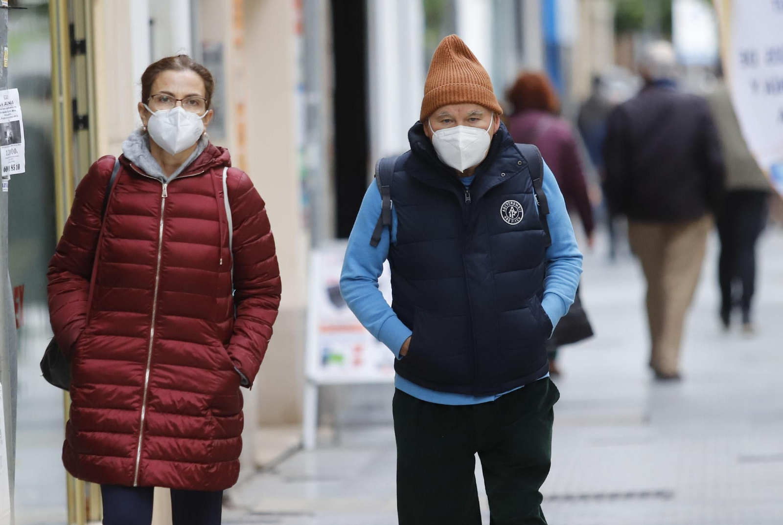 Dos onubenses pasean por la capital con sus mascarillas.