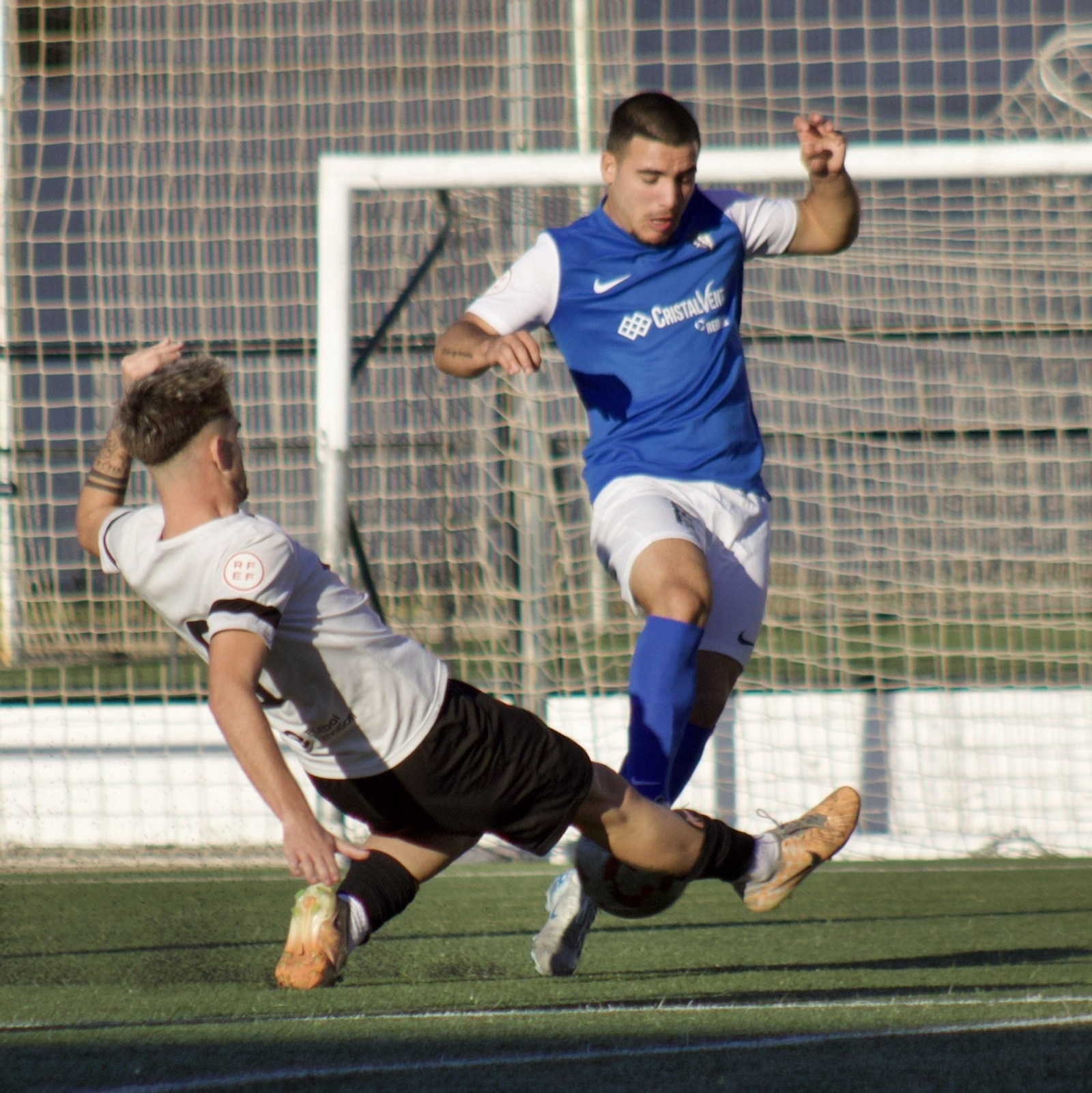 Un jugador cañaero realiza una entrada a ras de césped para intentar cortar una acción de los azulinos.