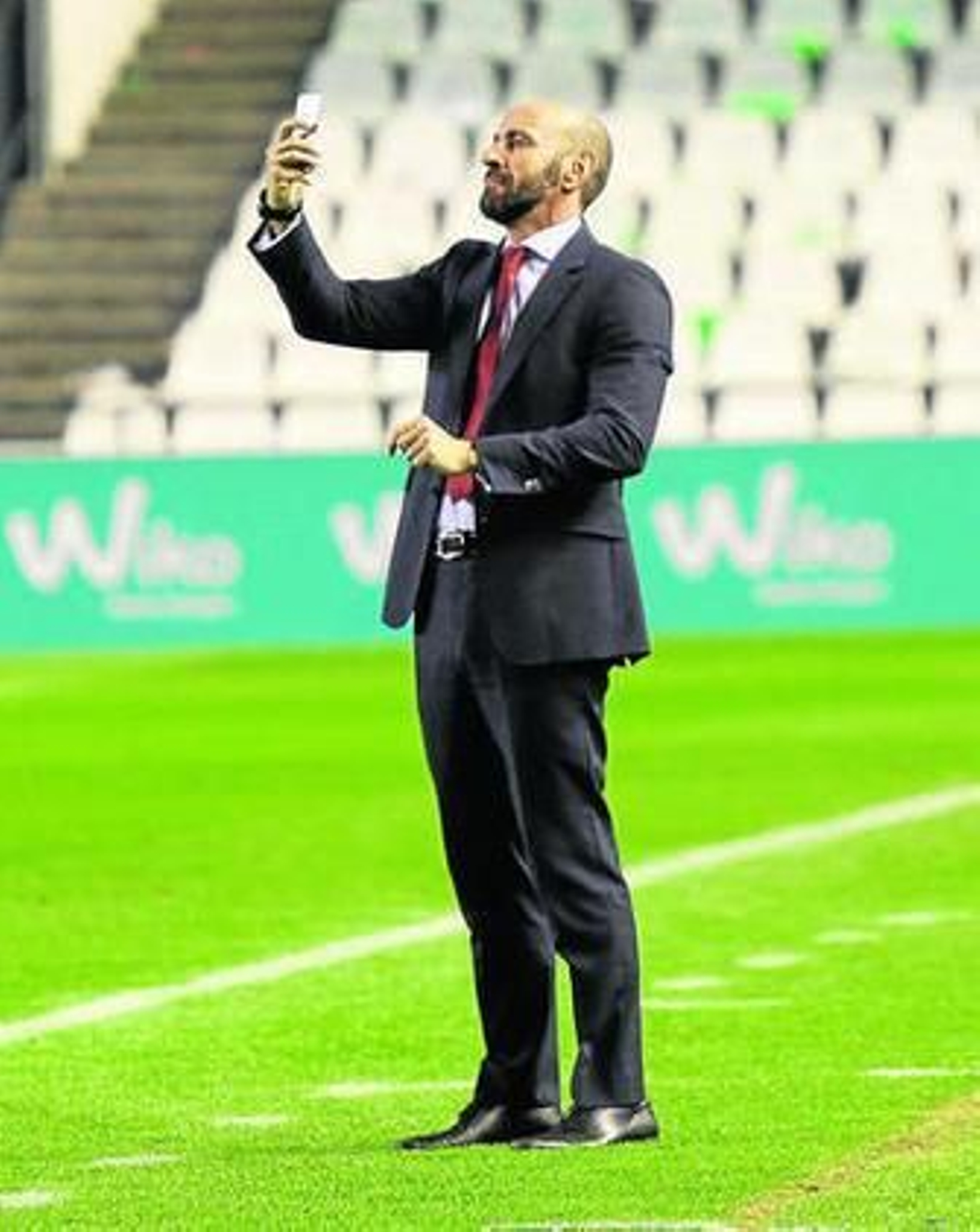 Monchi hace fotos a la afición sevillista desde el césped del Villamarín.