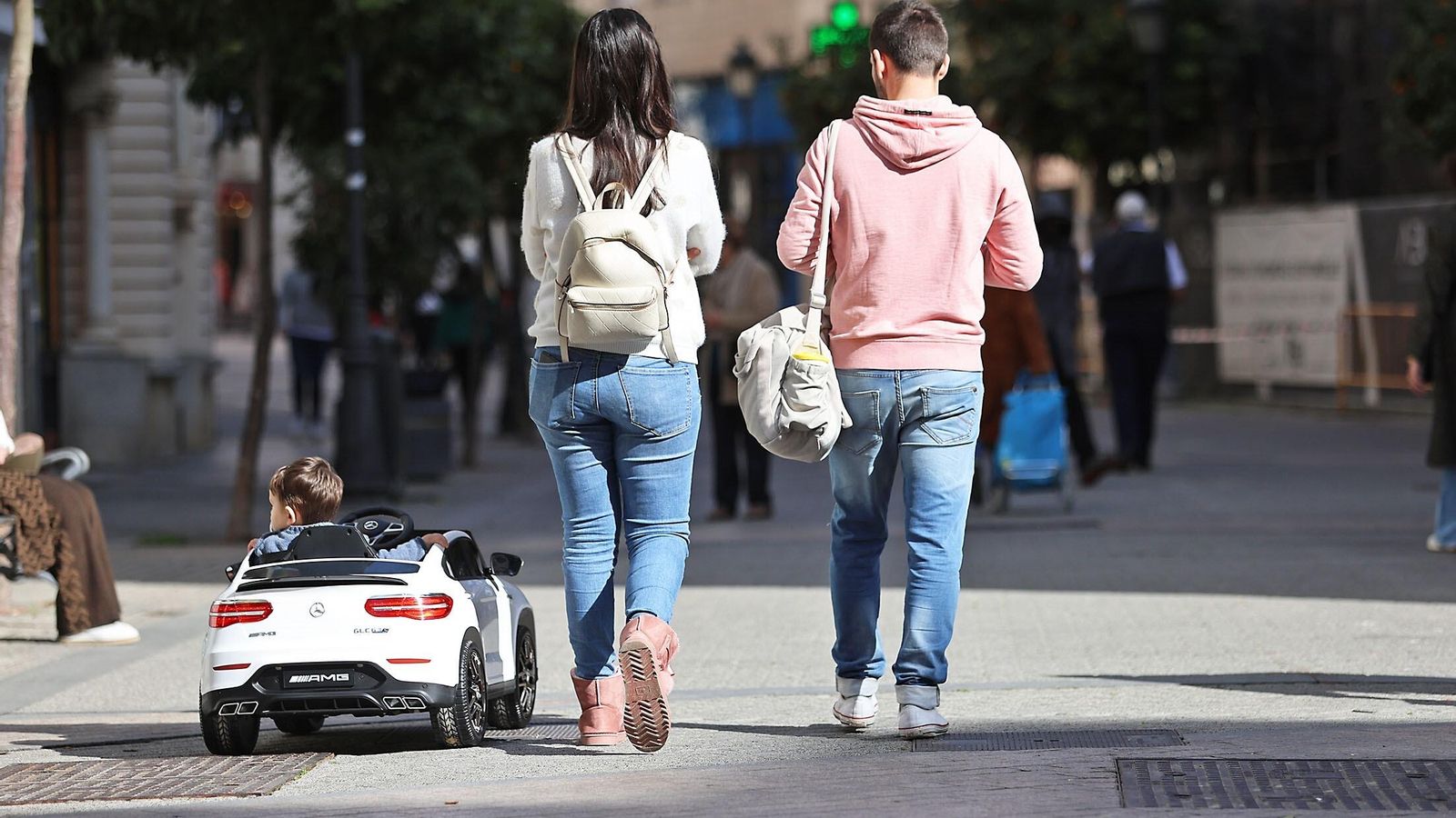 Los padres junto al hijo, que va en un cochecito por Huelva.