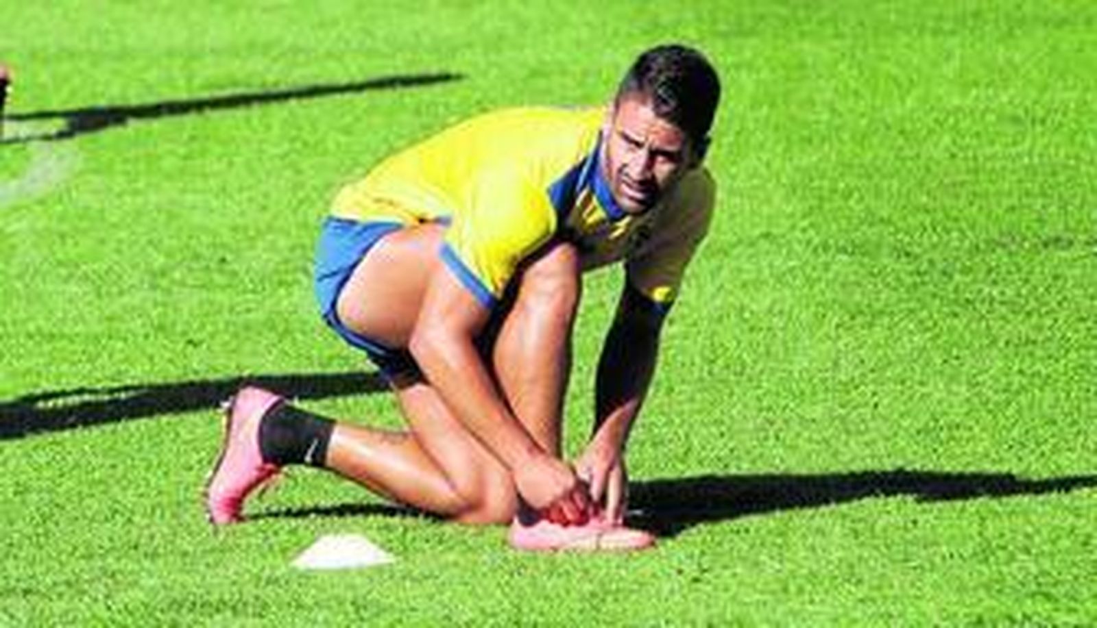 Kike Márquez se ata la bota derecha mientras atiende a las explicaciones del entrenador.