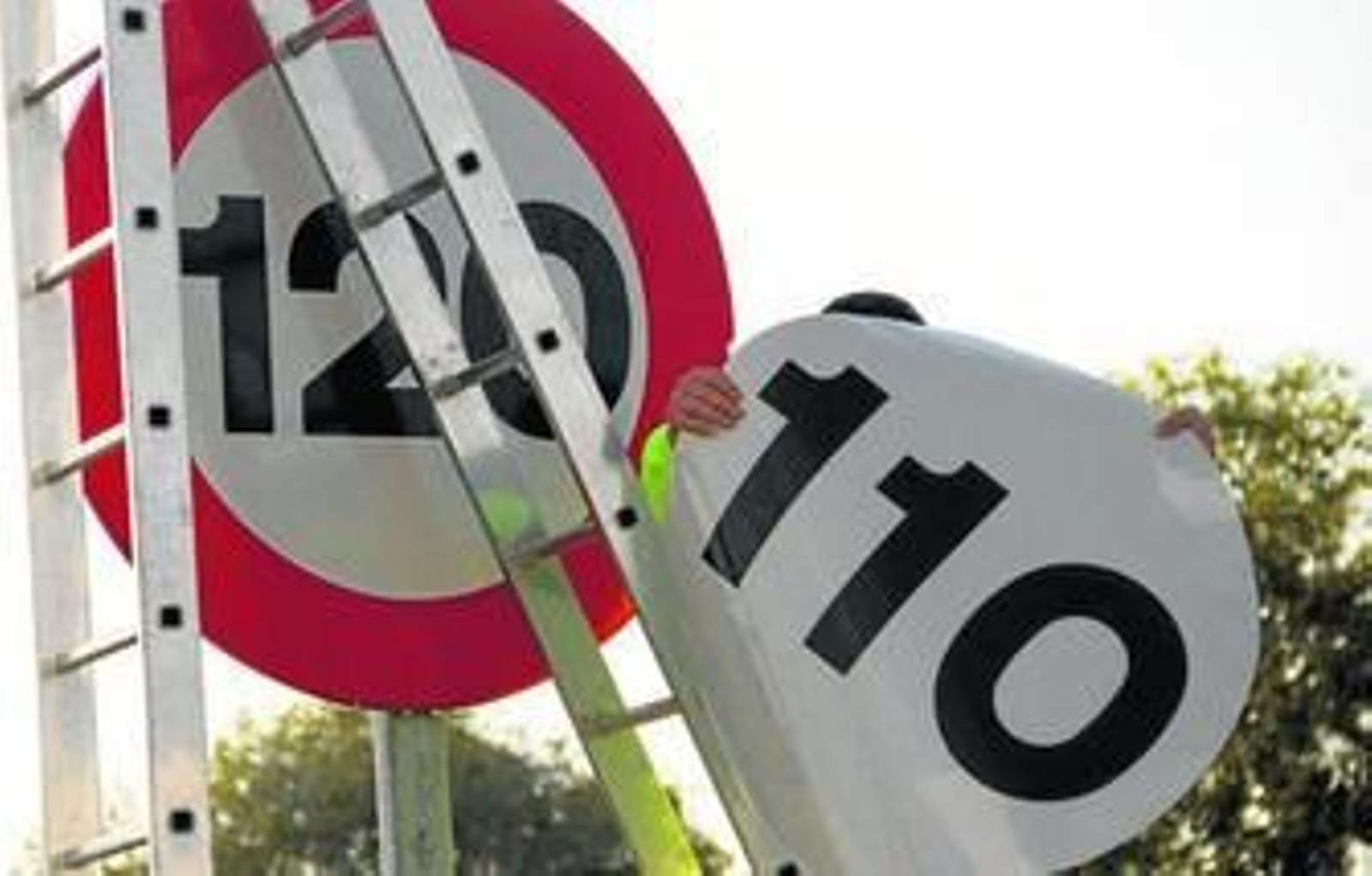 Un operario de conservación de carreteras se dispone a instalar la pegatina sobre una señal.