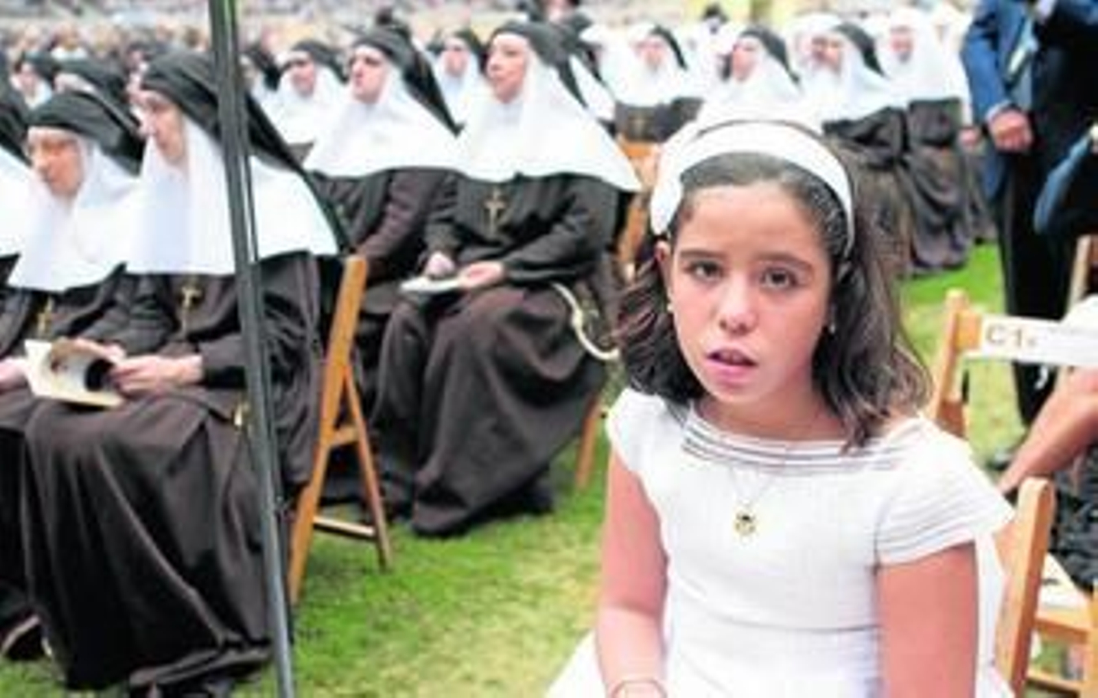La niña Ana María Rodríguez, junto a las hermanas de la Cruz, en el cesped del Estadio de la Cartuja.