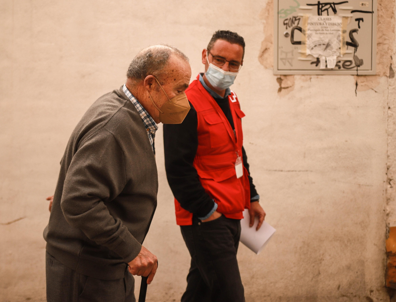 Un voluntario de Cruz Roja acompaña a una persona mayor.
