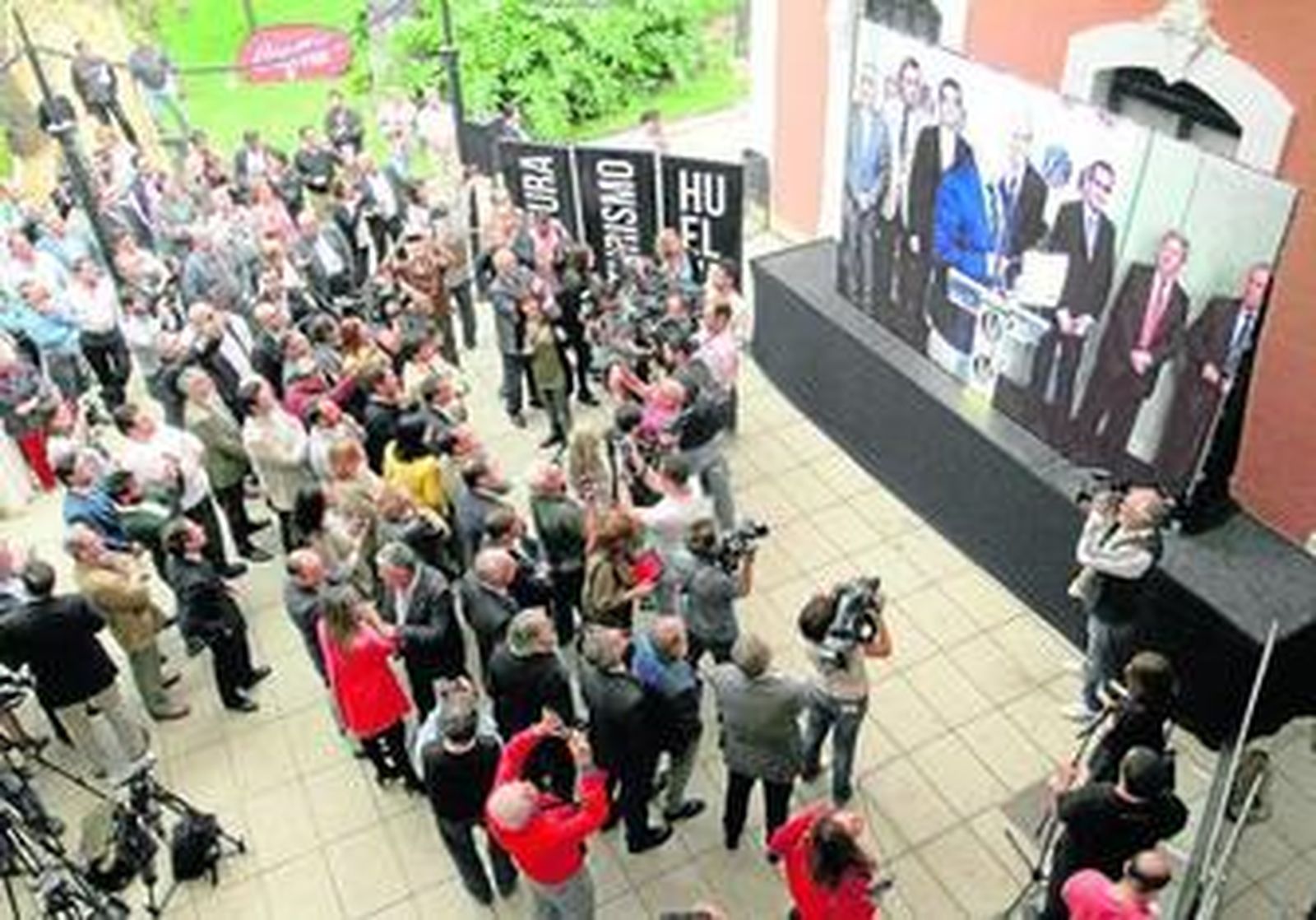 En la pantalla, Martín Bahamontes exhibe el cartel que acredita a Huelva como Capital Gastronómica ante la atenta mirada de los congregados en la Casa Colón.