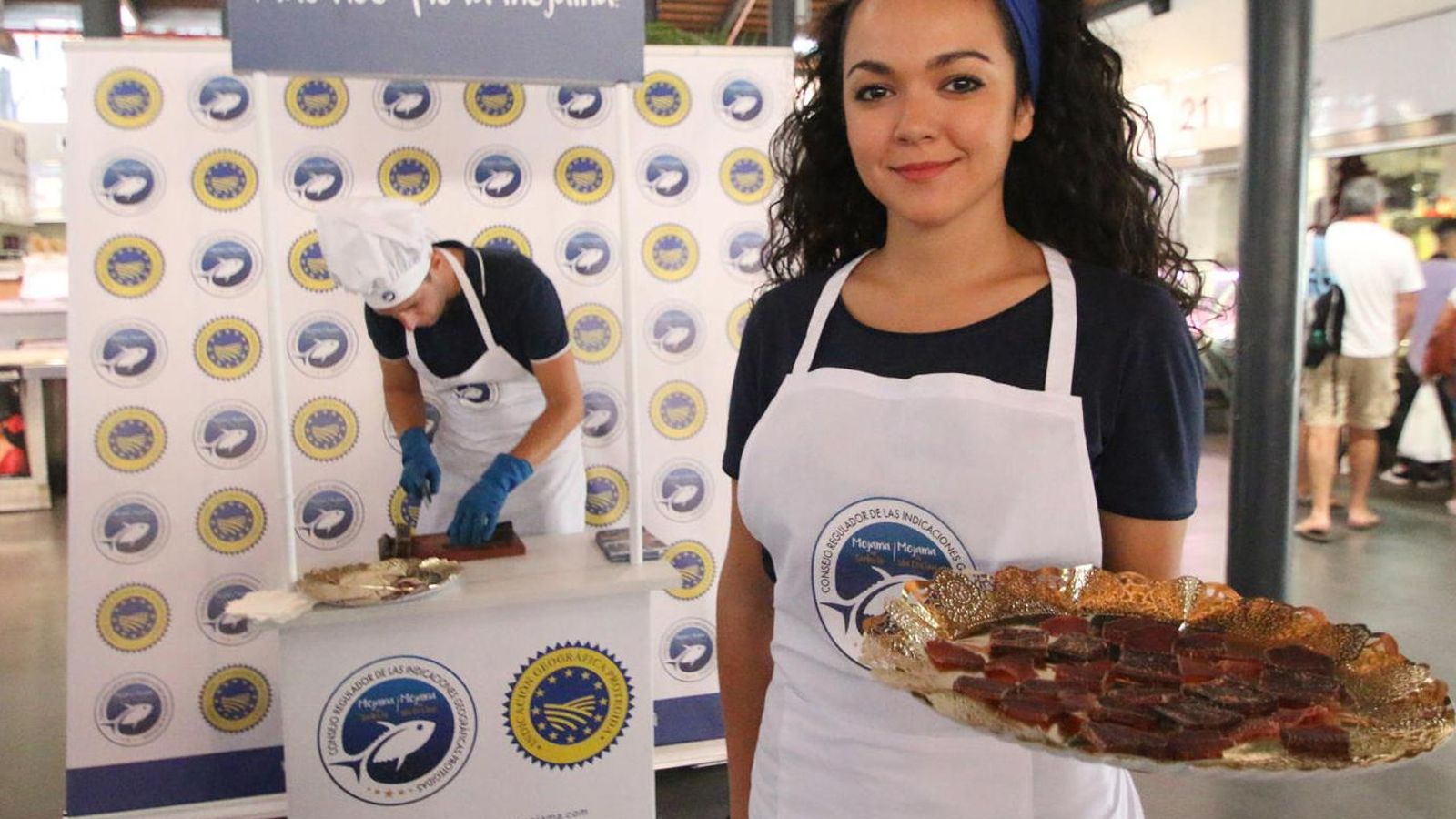 Una joven ofrece mojama en una feria gastronómica.