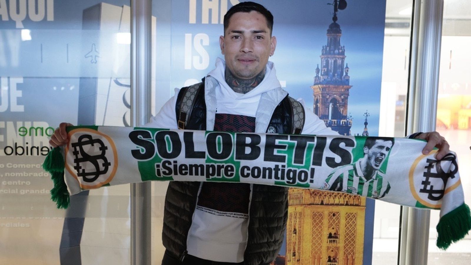 El Chimy Ávila posa con una bufanda del Betis a su llegada al Aeropuerto de San Pablo de la capital hispalense.