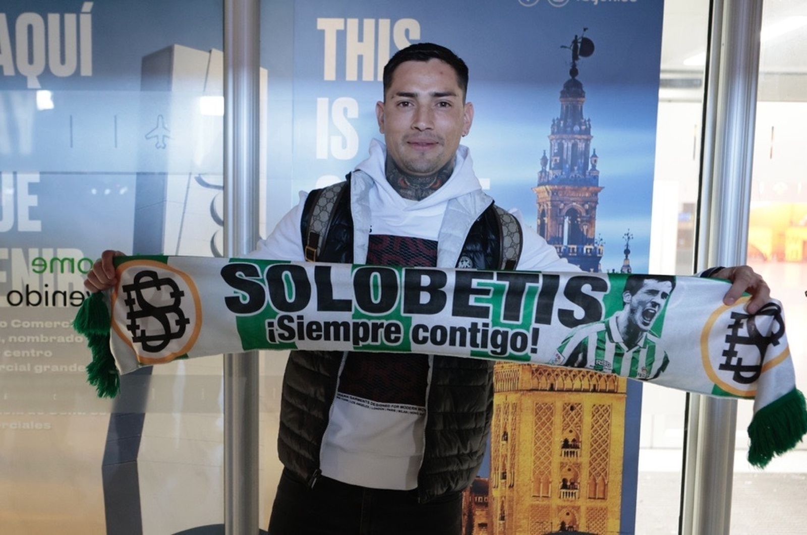 El Chimy Ávila posa con una bufanda del Betis a su llegada al Aeropuerto de San Pablo de la capital hispalense.