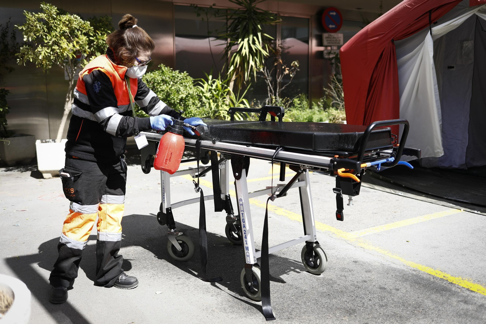 Una técnico de ambulancia desinfecta una camilla