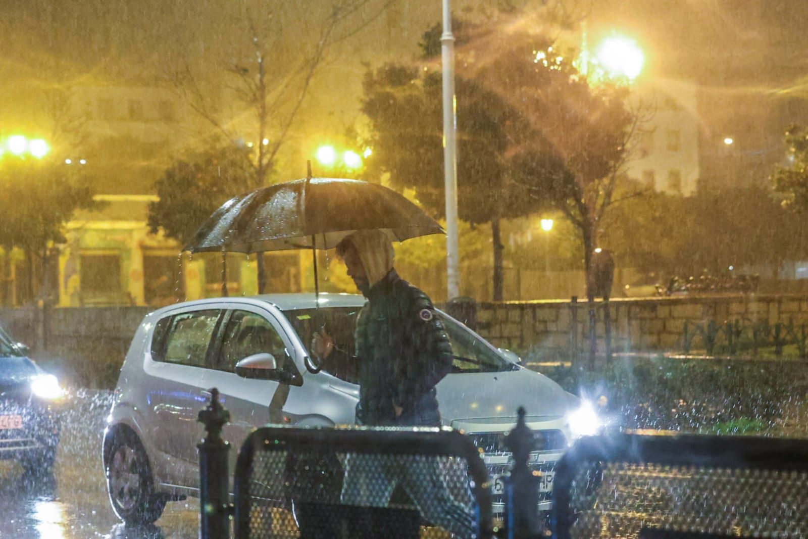 Una persona refugiándose de la lluvia con un paraguas.