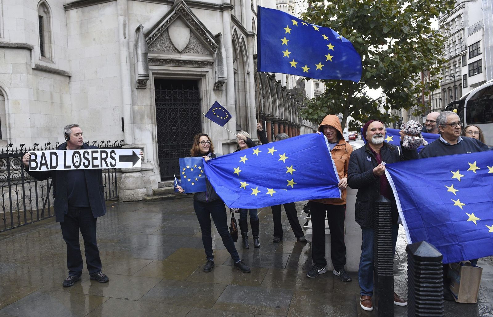 Manifestantes pro-Unión Europea se concentran en el exterior del Tribunal Superior de Londres (Reino Unido) al lado de un hombre que sostiene un cartel en el que se lee "malos perdedores".
