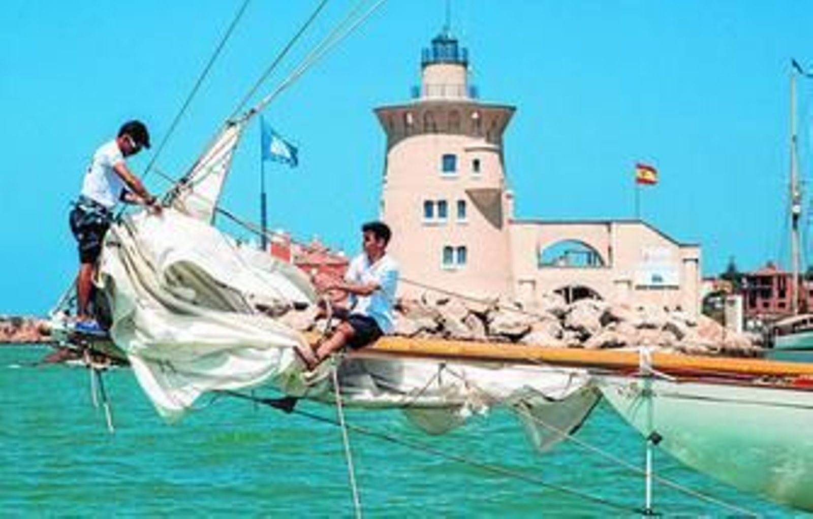 Algunos regatistas poniendo ayer a punto su barco justo delante del faro de Puerto Sherry.