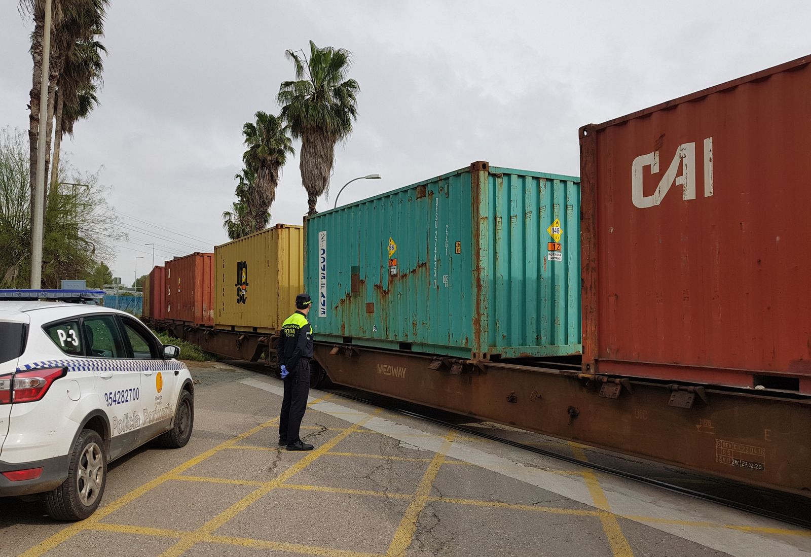 Un policía portuario observa el paso del tren con contenedores.
