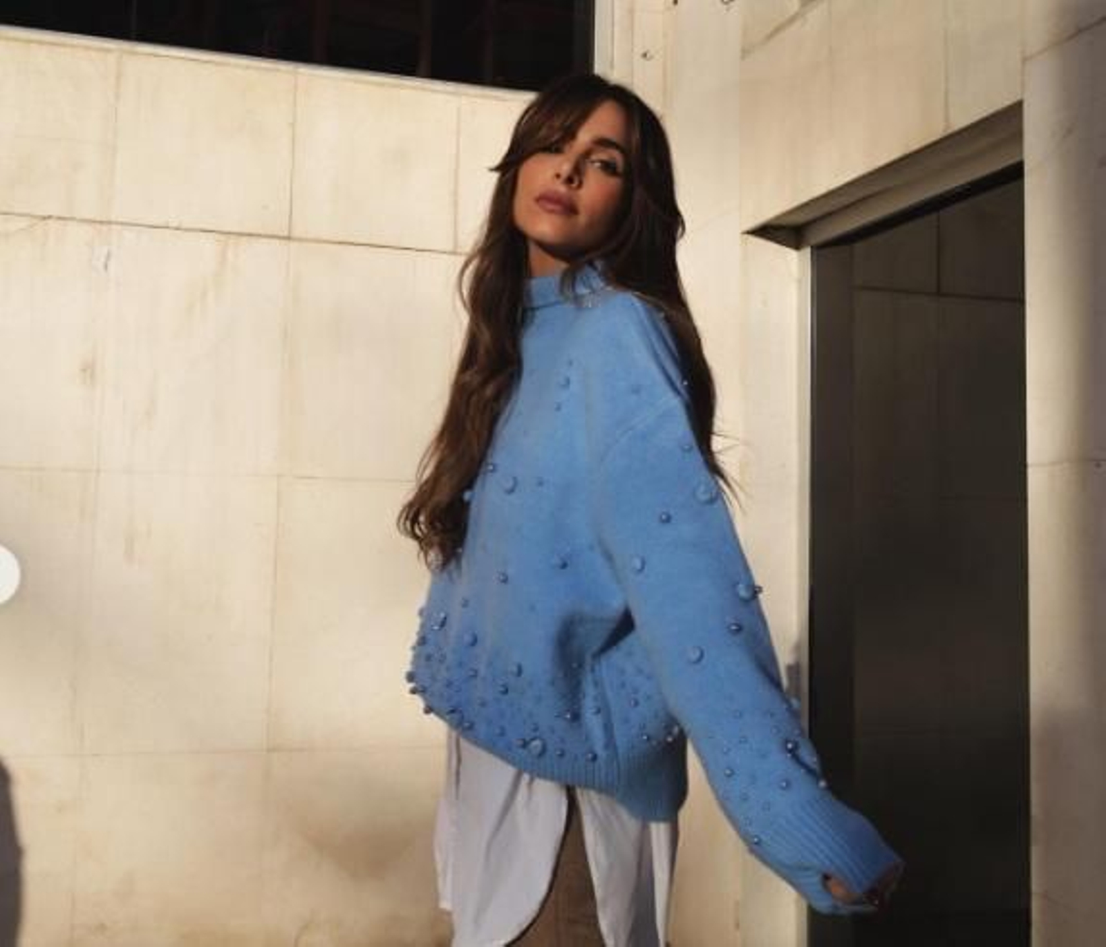 Rocío Osorno combina un jersey celeste con blusa blanca y pantalones camel.