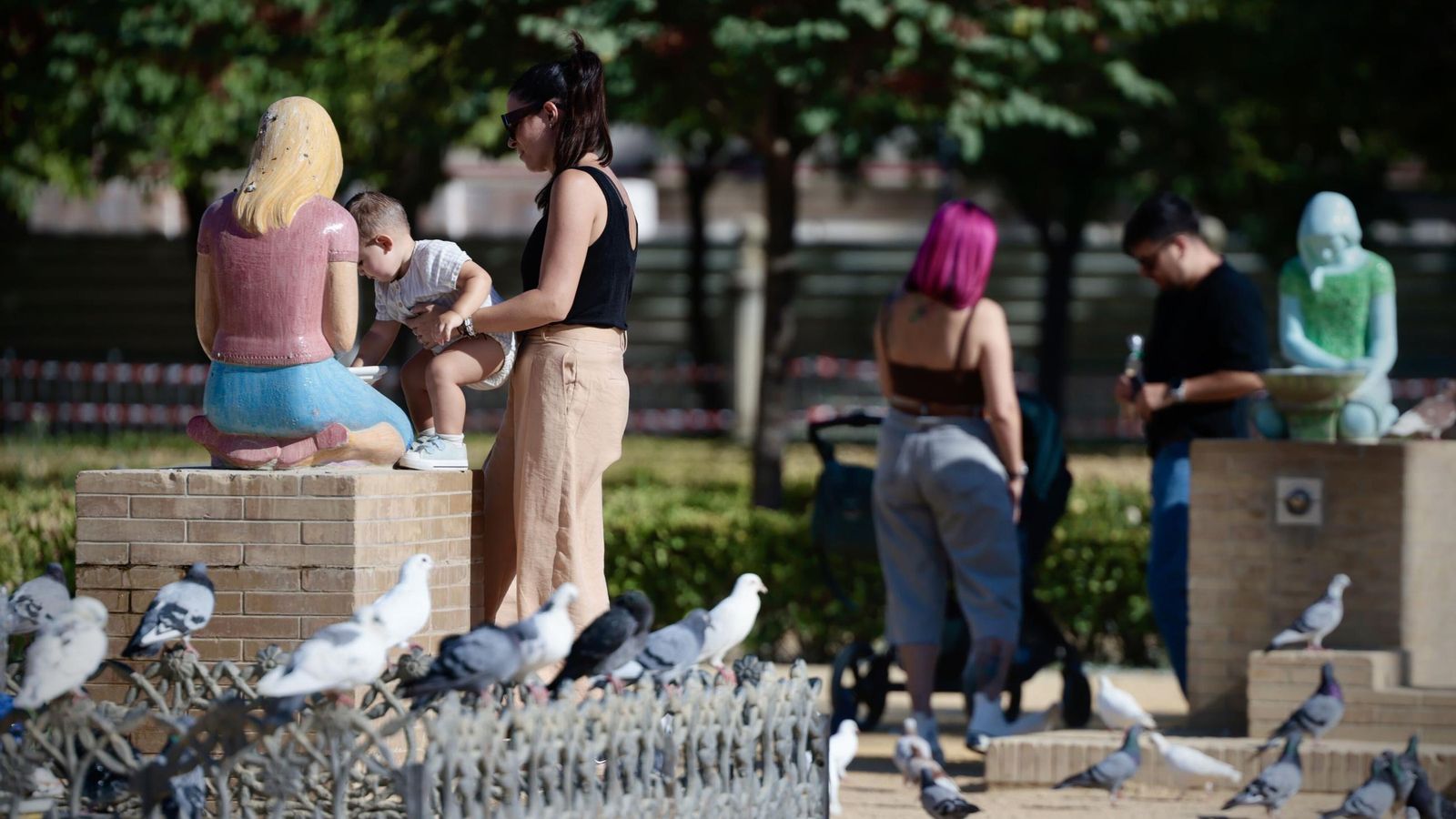Varias personas rodeadas de palomas en la plaza de América