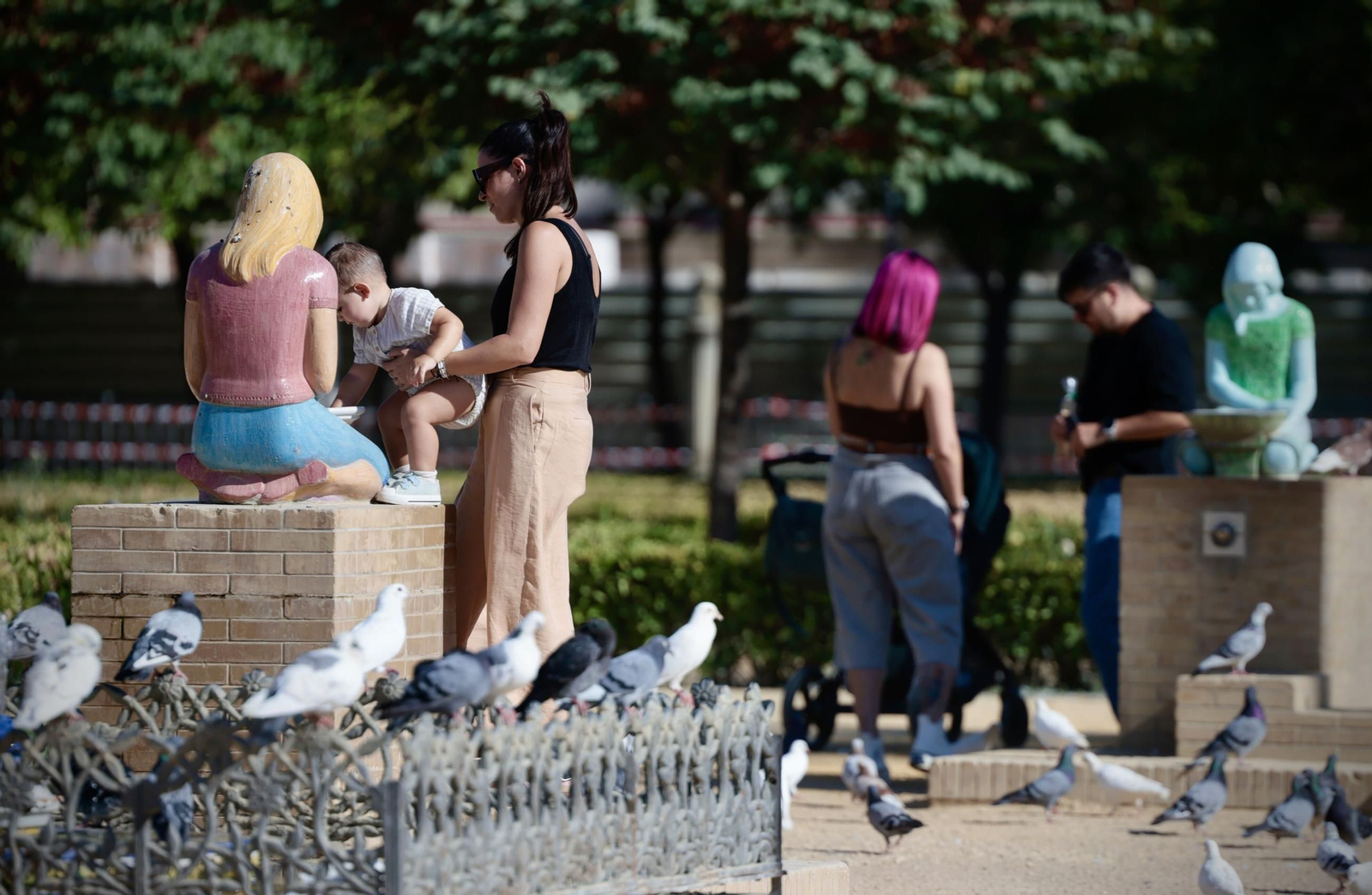 Varias personas rodeadas de palomas en la plaza de América.