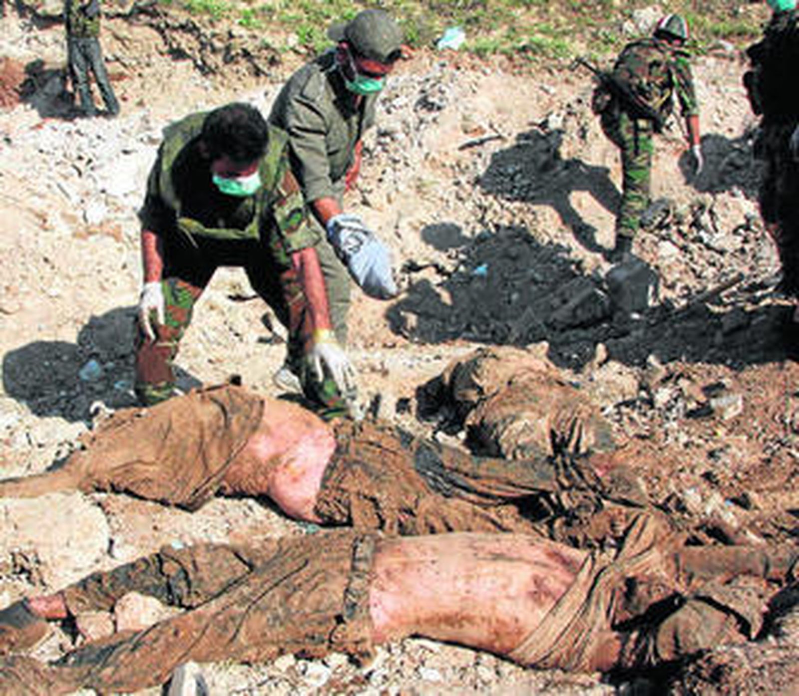 Soldados sirios revisan los cuerpos de diez policías torturados y enterrados en una fosa común.