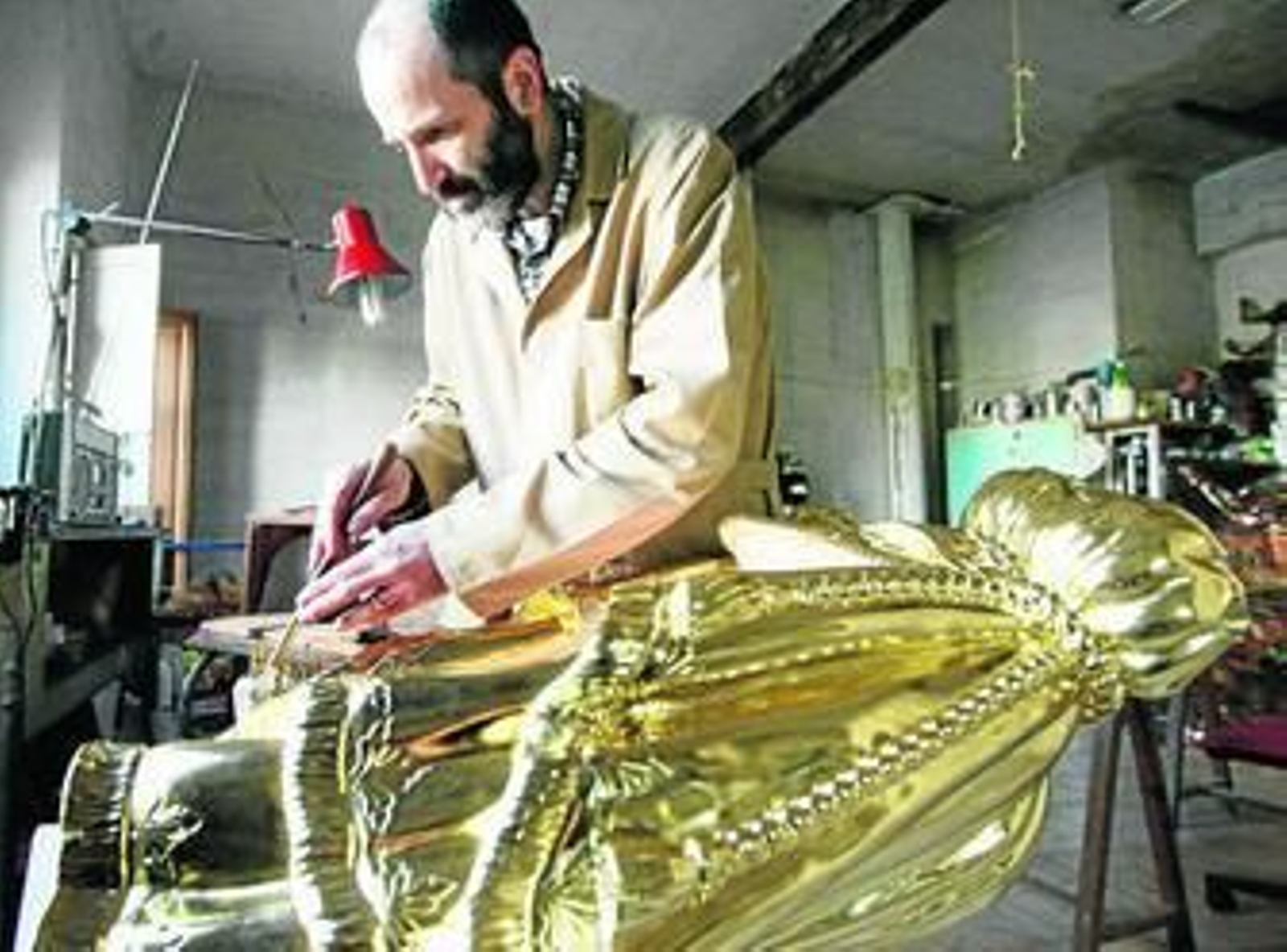 Uno de lo trabajadores del taller de Miguel Arjona trabaja en el dorado del templete.