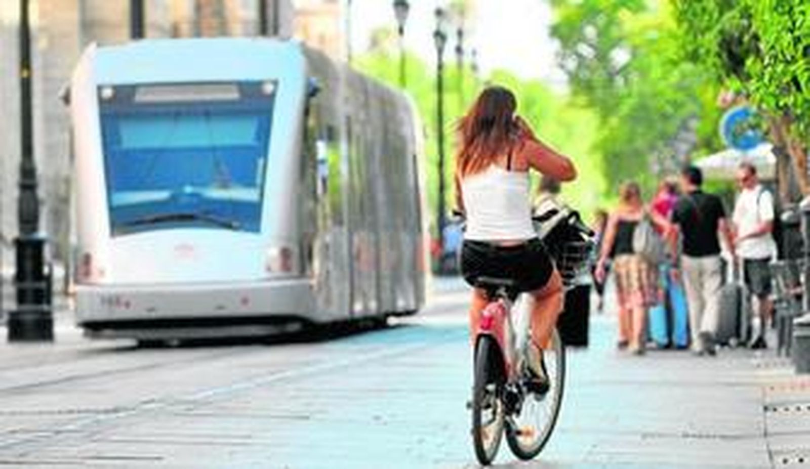 Una joven pedalea mientras habla por su teléfono móvil en la Avenida de la Constitución, el pasado viernes.