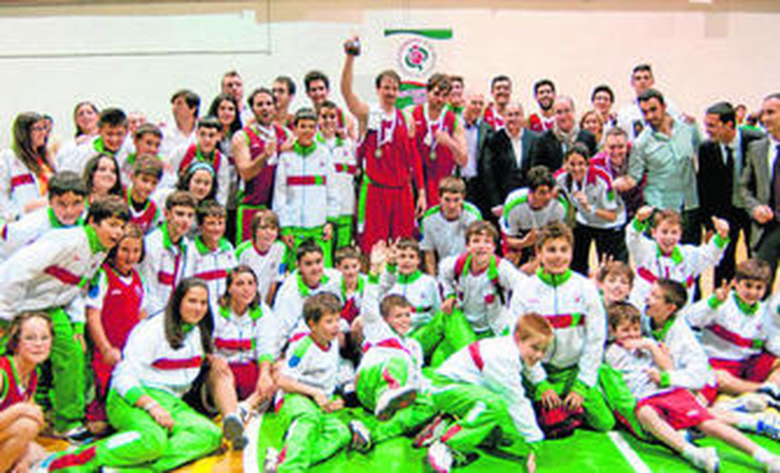 Los jugadores de la escuadra granadina posan con el trofeo y acompañados por niños de la cantera.