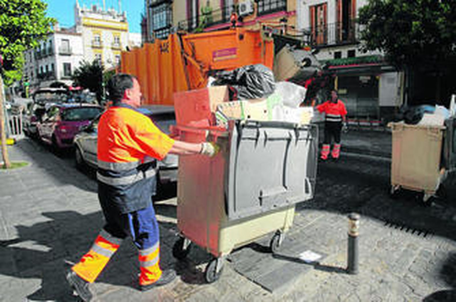 Un operario de Lipasam retira un contenedor para vaciarlo de basura.