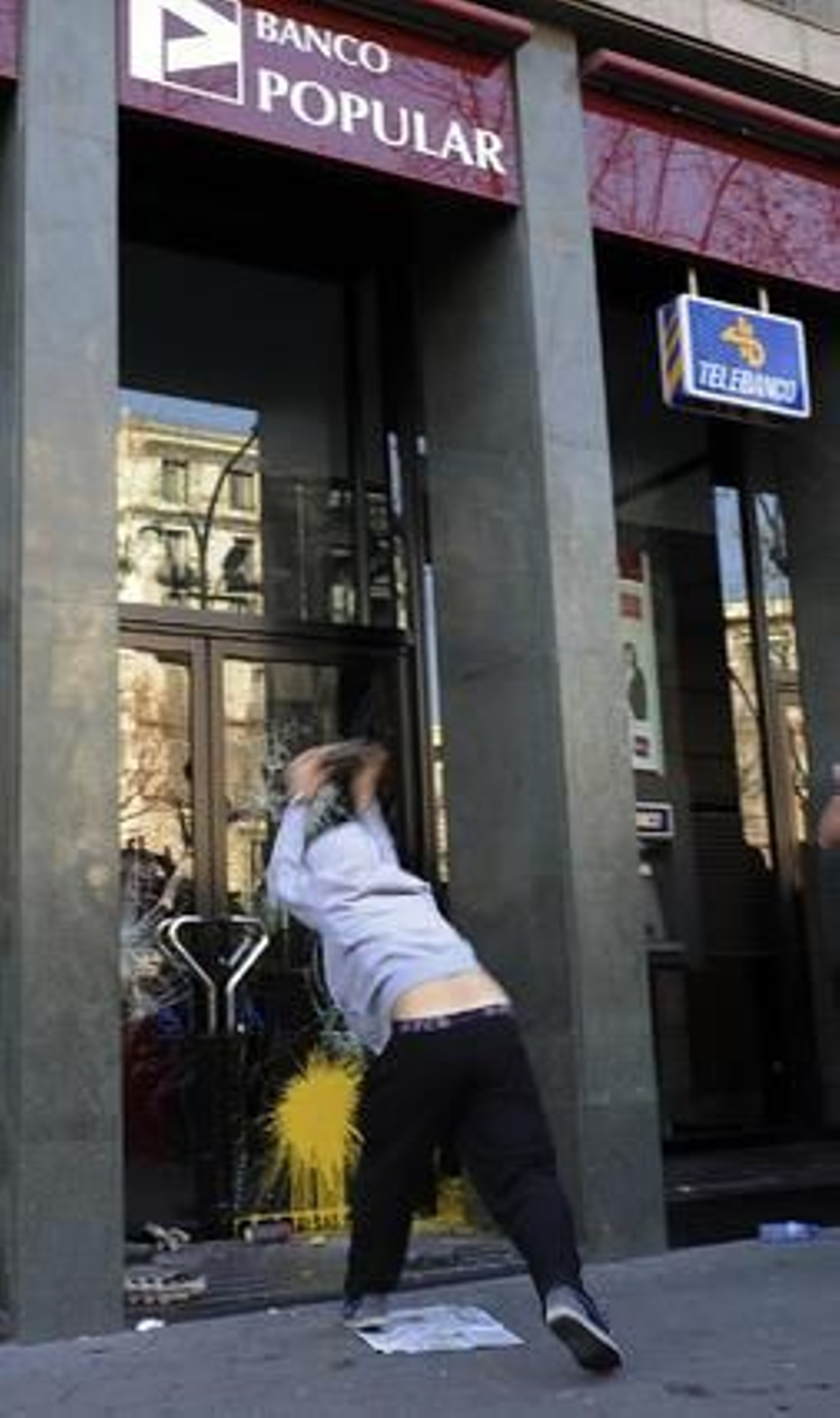 Un joven lanza piedras y bolas de pintura contra un banco.

Foto: AFP Photo