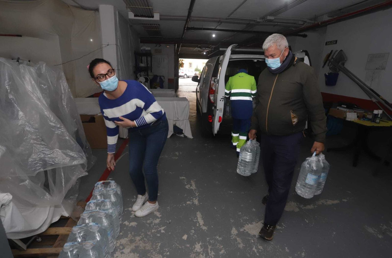 Vecinos de La Alcaidesa recogen garrafas de agua, este miércoles.