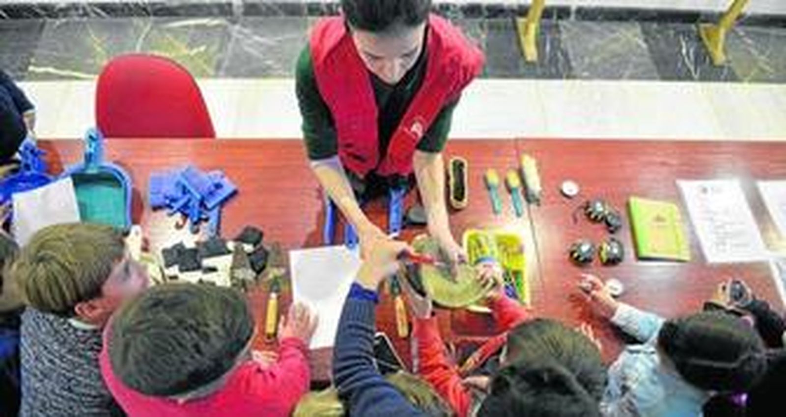 1. La arqueóloga Balbina Ruiz enseña a los pequeños a manipular una pieza de barro en la mesa en la que están las herramientas del taller. 2. Presentación de diapositivas creada por Activamentes para explicar nociones de arqueología.