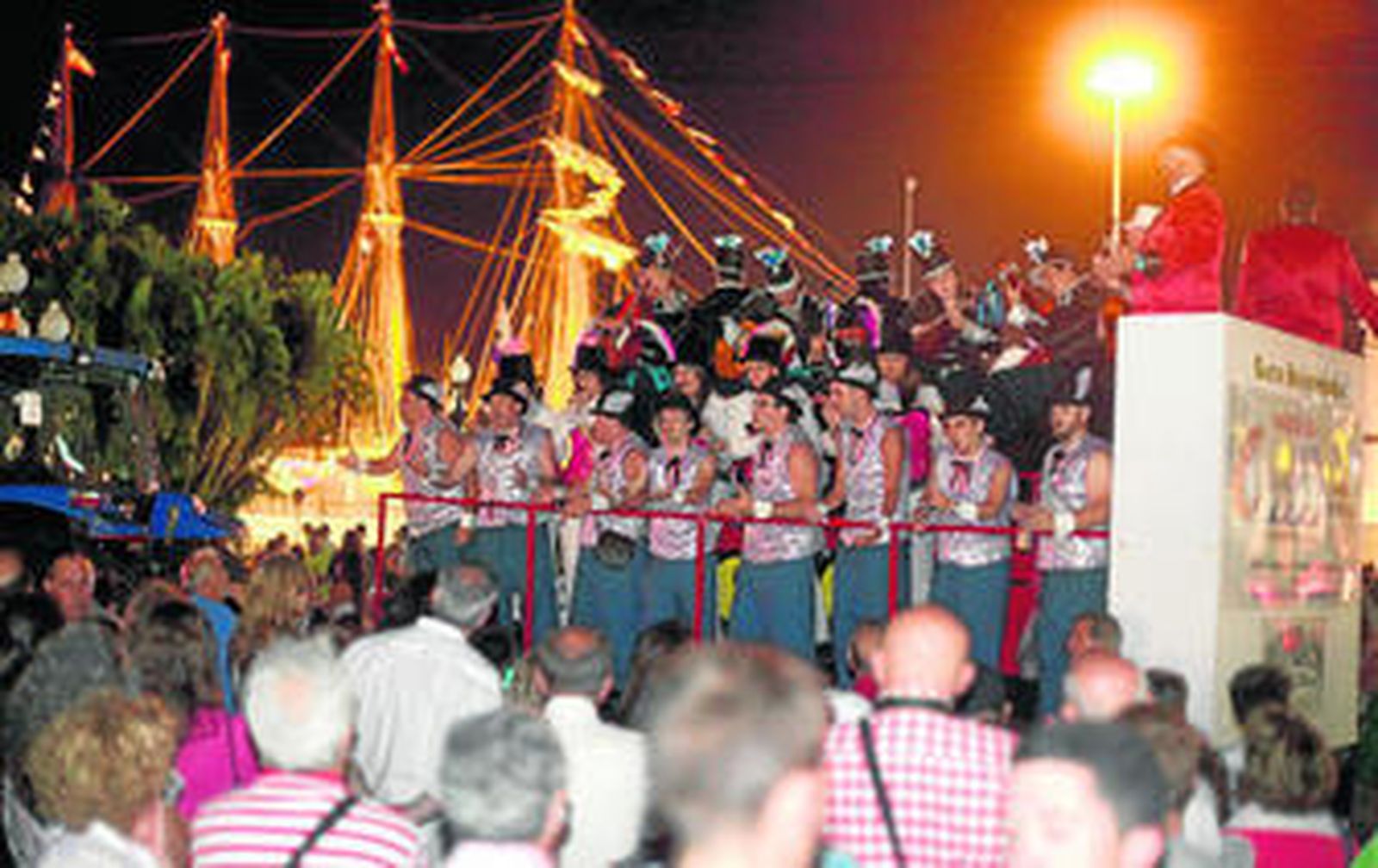 El coro 'Teatro Barvariedades' canta en su batea con el 'Juan Sebastián Elcano' al fondo.