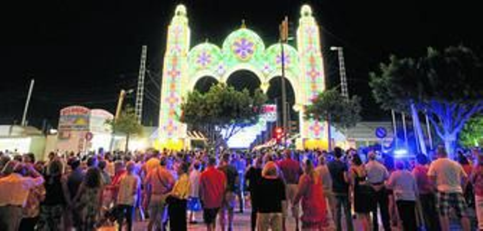 Ciudadanos ante la portada, poco después de ser iluminada el primer día de Feria del Carmen.