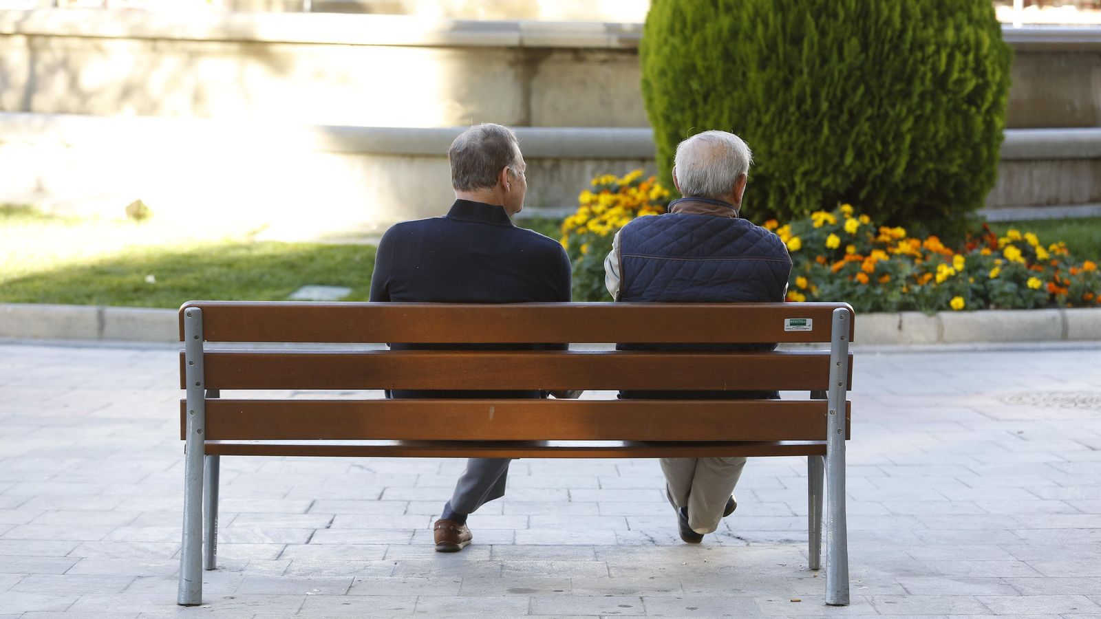 Dos hombres sentados en los bancos de la Fuente de las Batallas de Granada