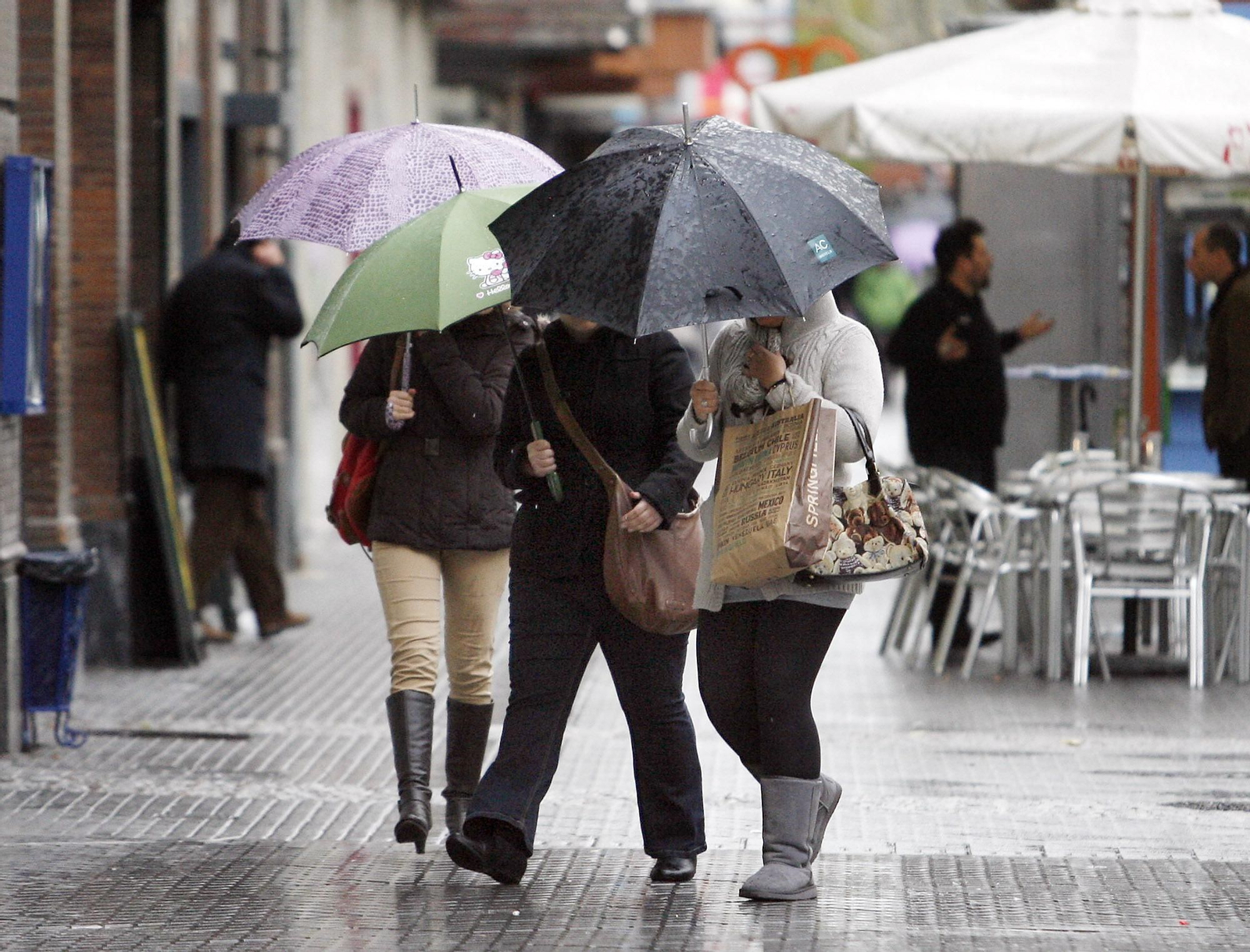 Varias personas se protegen de la lluvia bajo paraguas.