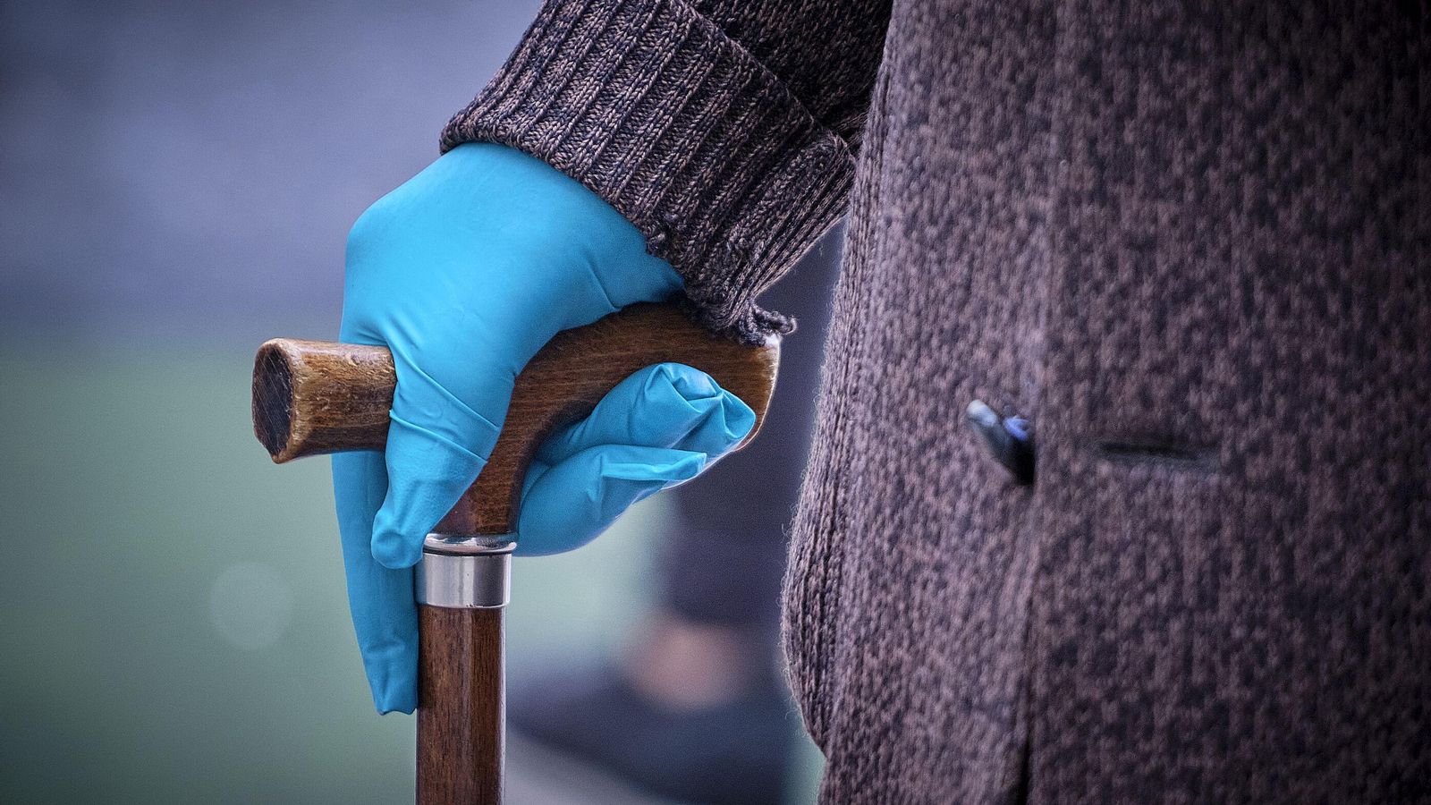 Una persona mayor camina protegida con guantes cerca de un supermercado de Cádiz durante el primer estado de alarma.