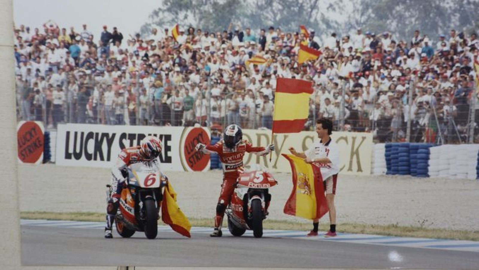 Alberto Puig toma una bandera de España para celebrar su triunfo en Jerez el 7 de mayo de 1995, junto a un Crivillé que también subió al podio