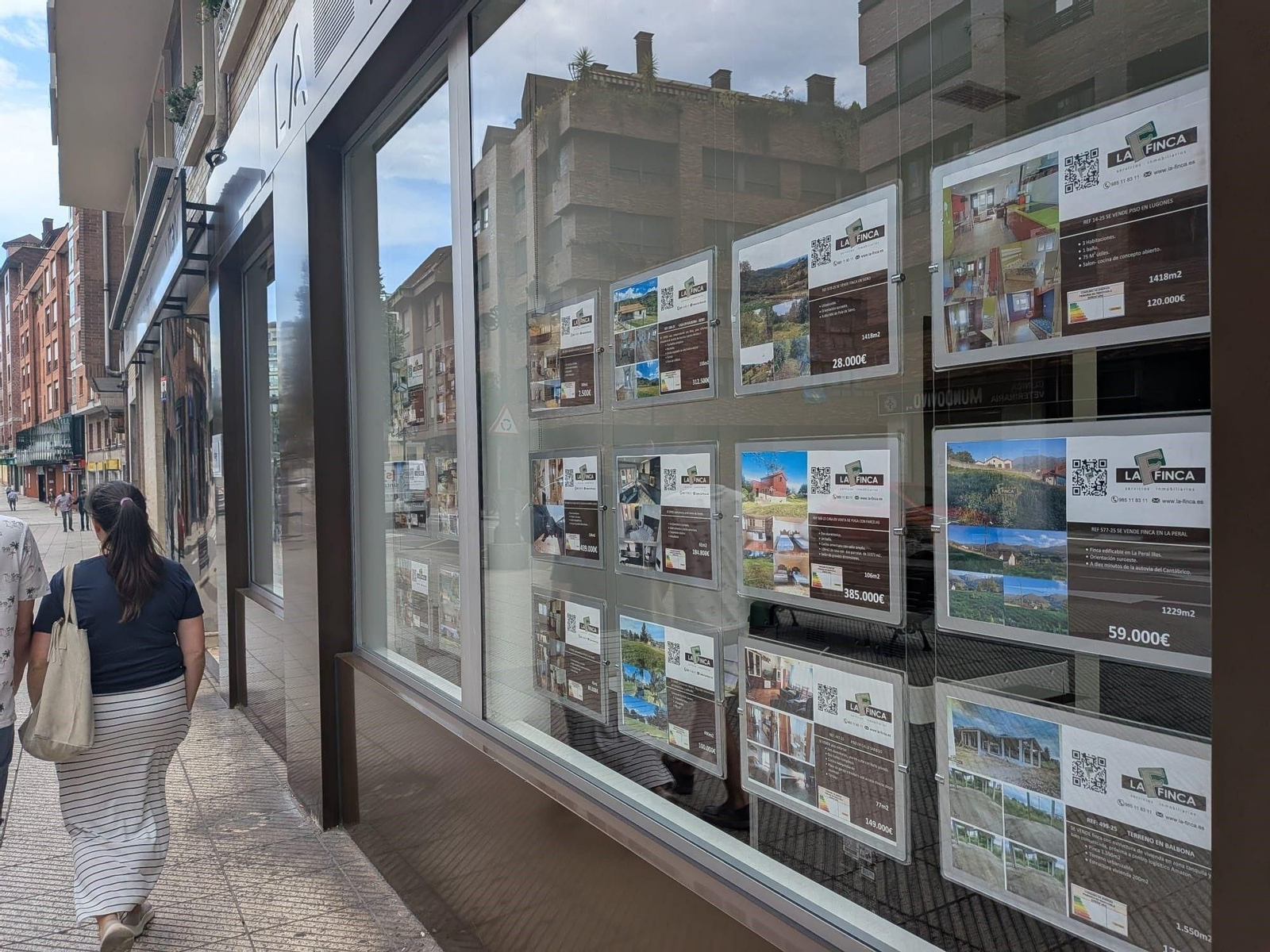 Una pareja pasando frente al escaparate de una inmobiliaria